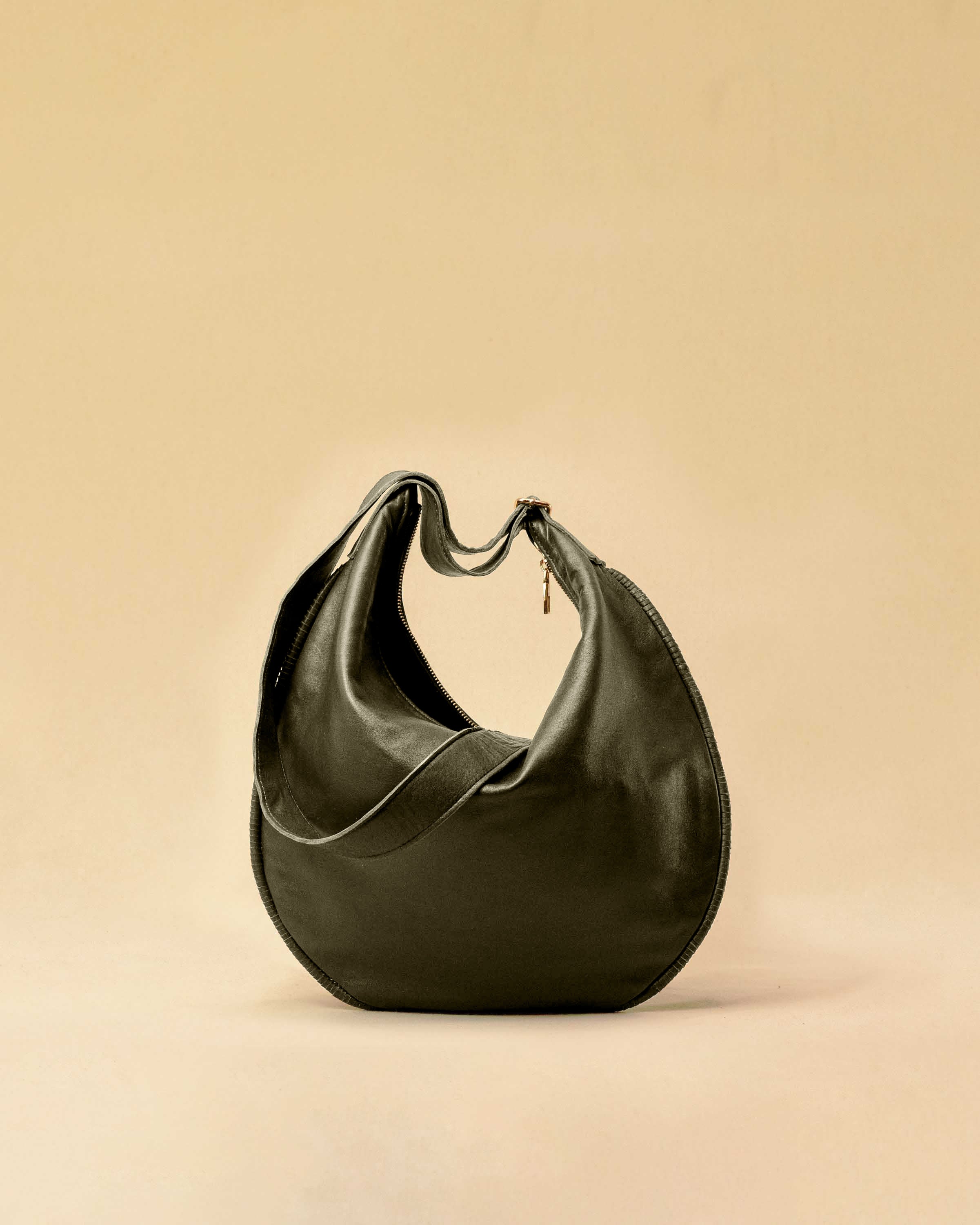 The Saddle Bag IVY by LABEL17 is crafted from supple, vegetable-tanned nappa leather and defined by its distinctive hand-stitched side seams. Its softly curved saddle silhouette rests comfortably against the body. The bag features a zip closure, a leather-lined interior, and a secure inner pocket. The adjustable strap allows it to be worn over the shoulder or crossbody – a versatile piece for everyday use. Handmade in Morocco.