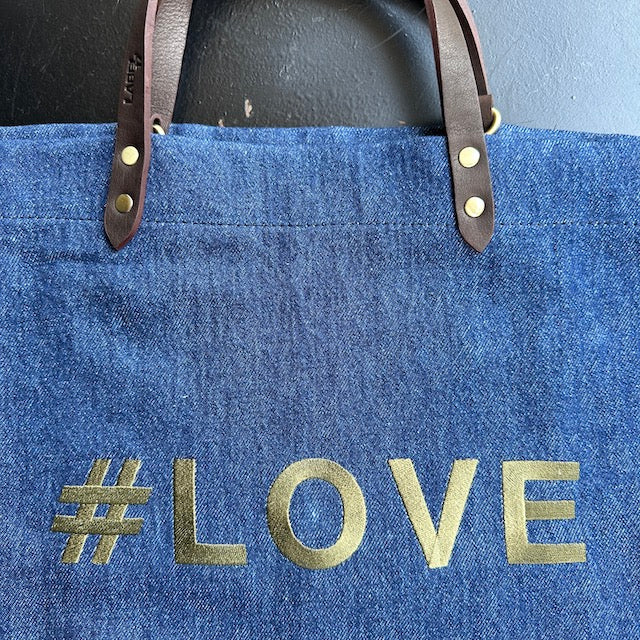 Bestickte Stofftasche von LABEL17 mit braunen Lederhenkeln und #LOVE Botschaft auf der Vorderseite. Hergestellt in Marokko