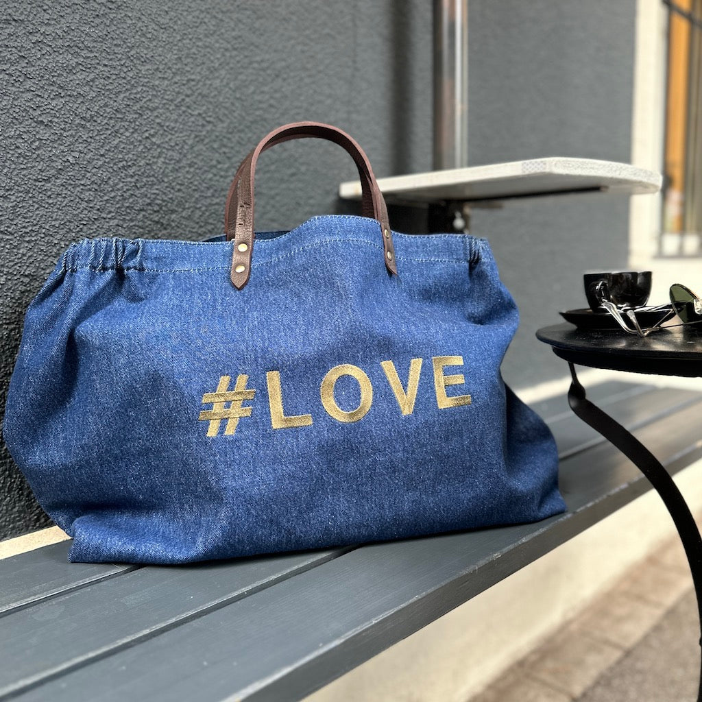 Bestickte Stofftasche von LABEL17 mit braunen Lederhenkeln und #LOVE Botschaft auf der Vorderseite. Hergestellt in Marokko