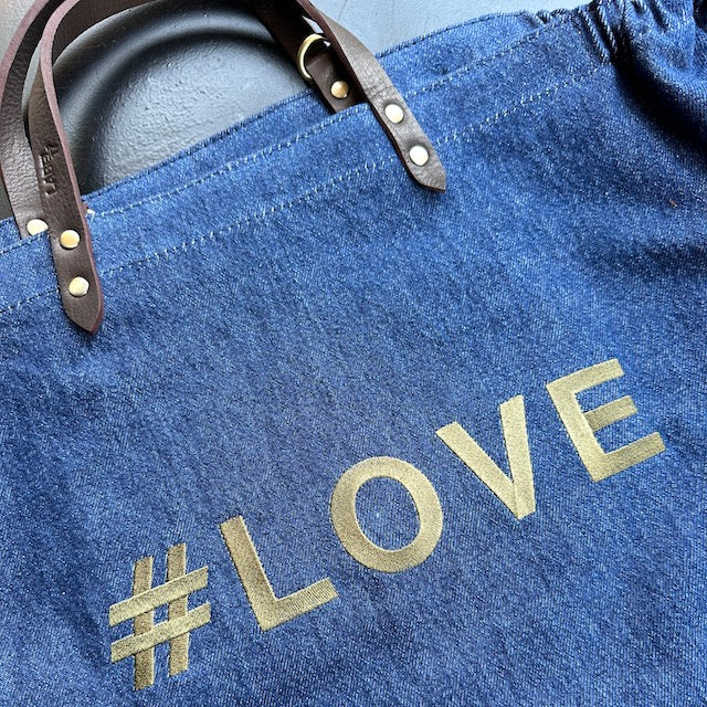 Bestickte Stofftasche von LABEL17 mit braunen Lederhenkeln und #LOVE Botschaft auf der Vorderseite. Hergestellt in Marokko
