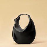 The Saddle Bag IVY by LABEL17 is crafted from supple, vegetable-tanned nappa leather and defined by its distinctive hand-stitched side seams. Its softly curved saddle silhouette rests comfortably against the body. The bag features a zip closure, a leather-lined interior, and a secure inner pocket. The adjustable strap allows it to be worn over the shoulder or crossbody – a versatile piece for everyday use. Handmade in Morocco.