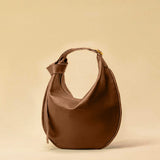 The Saddle Bag IVY by LABEL17 is crafted from supple, vegetable-tanned nappa leather and defined by its distinctive hand-stitched side seams. Its softly curved saddle silhouette rests comfortably against the body. The bag features a zip closure, a leather-lined interior, and a secure inner pocket. The adjustable strap allows it to be worn over the shoulder or crossbody – a versatile piece for everyday use. Handmade in Morocco.