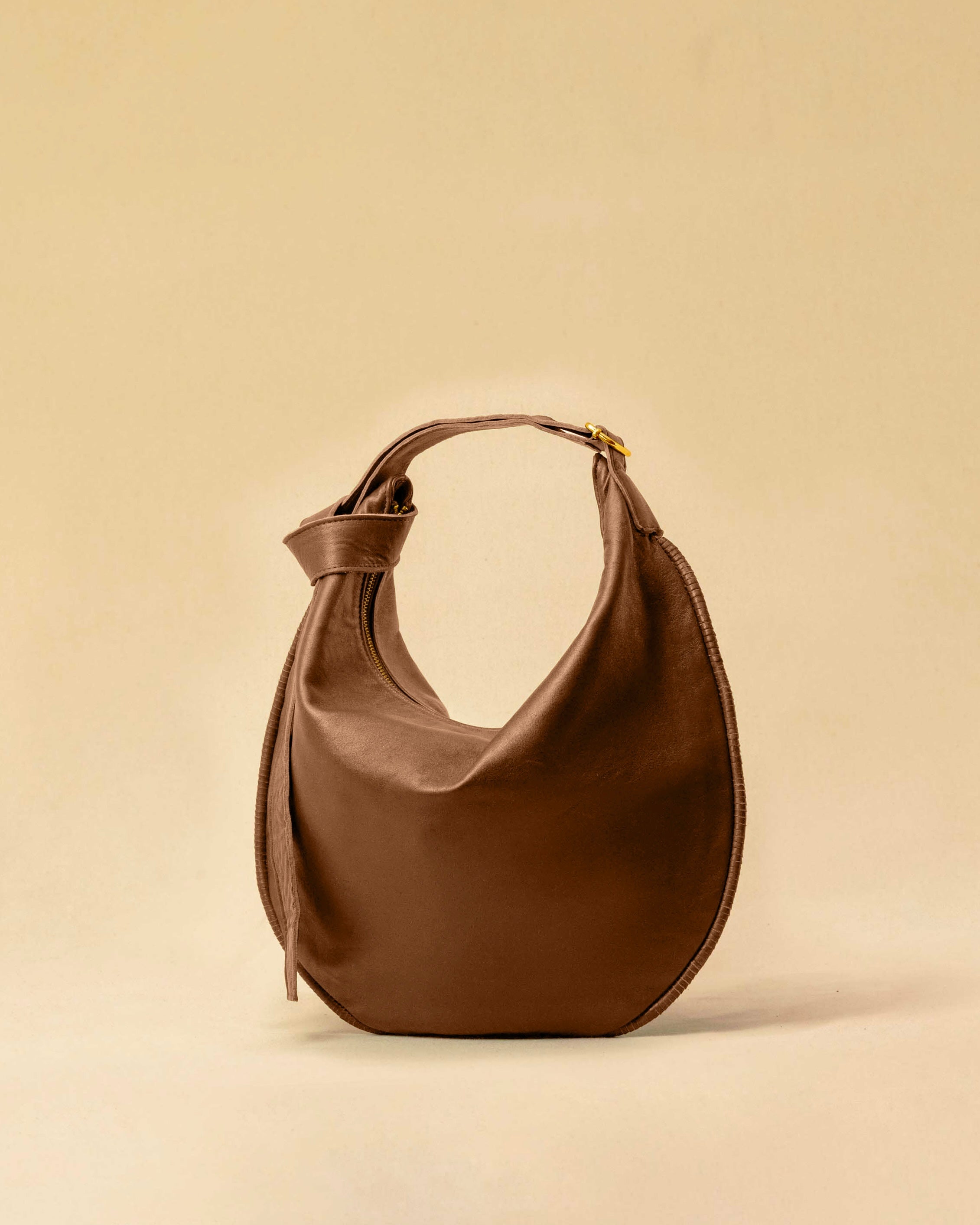 The Saddle Bag IVY by LABEL17 is crafted from supple, vegetable-tanned nappa leather and defined by its distinctive hand-stitched side seams. Its softly curved saddle silhouette rests comfortably against the body. The bag features a zip closure, a leather-lined interior, and a secure inner pocket. The adjustable strap allows it to be worn over the shoulder or crossbody – a versatile piece for everyday use. Handmade in Morocco.