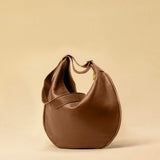 The Saddle Bag IVY by LABEL17 is crafted from supple, vegetable-tanned nappa leather and defined by its distinctive hand-stitched side seams. Its softly curved saddle silhouette rests comfortably against the body. The bag features a zip closure, a leather-lined interior, and a secure inner pocket. The adjustable strap allows it to be worn over the shoulder or crossbody – a versatile piece for everyday use. Handmade in Morocco.