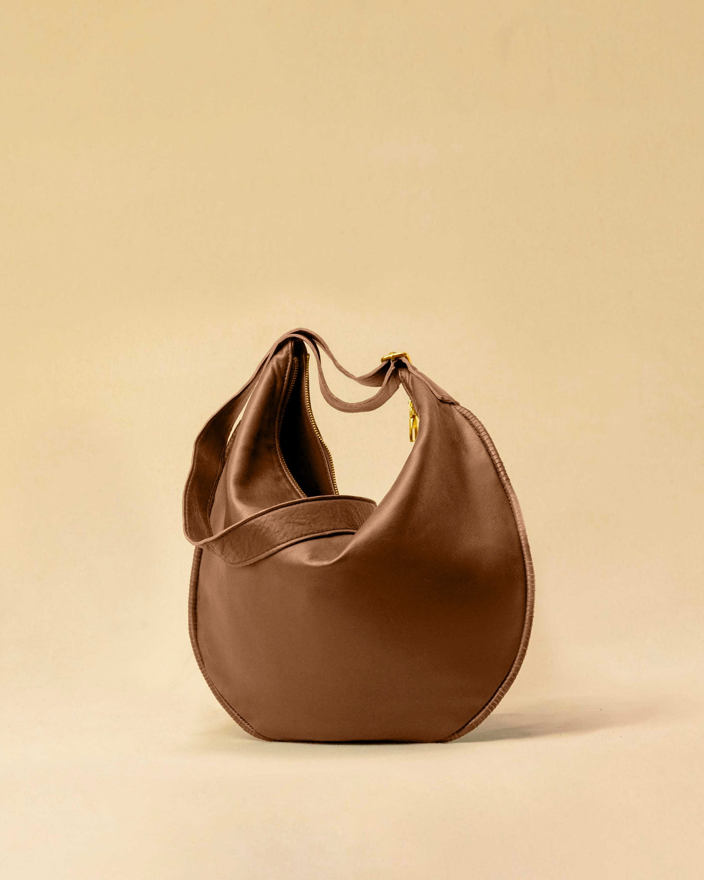 The Saddle Bag IVY by LABEL17 is crafted from supple, vegetable-tanned nappa leather and defined by its distinctive hand-stitched side seams. Its softly curved saddle silhouette rests comfortably against the body. The bag features a zip closure, a leather-lined interior, and a secure inner pocket. The adjustable strap allows it to be worn over the shoulder or crossbody – a versatile piece for everyday use. Handmade in Morocco.