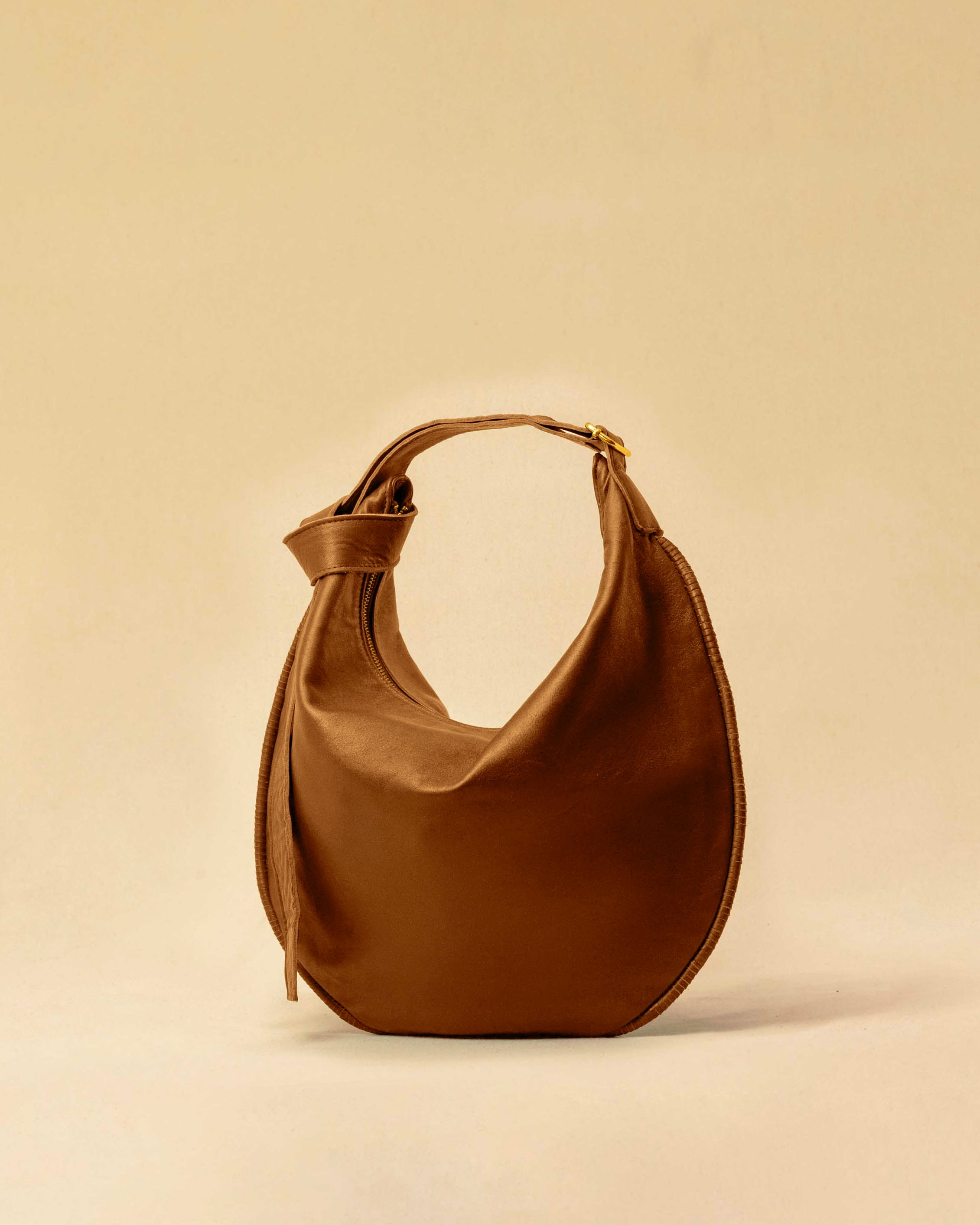 The Saddle Bag IVY by LABEL17 is crafted from supple, vegetable-tanned nappa leather and defined by its distinctive hand-stitched side seams. Its softly curved saddle silhouette rests comfortably against the body. The bag features a zip closure, a leather-lined interior, and a secure inner pocket. The adjustable strap allows it to be worn over the shoulder or crossbody – a versatile piece for everyday use. Handmade in Morocco.