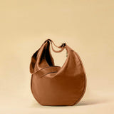 The Saddle Bag IVY by LABEL17 is crafted from supple, vegetable-tanned nappa leather and defined by its distinctive hand-stitched side seams. Its softly curved saddle silhouette rests comfortably against the body. The bag features a zip closure, a leather-lined interior, and a secure inner pocket. The adjustable strap allows it to be worn over the shoulder or crossbody – a versatile piece for everyday use. Handmade in Morocco.