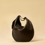 The Saddle Bag IVY by LABEL17 is crafted from supple, vegetable-tanned nappa leather and defined by its distinctive hand-stitched side seams. Its softly curved saddle silhouette rests comfortably against the body. The bag features a zip closure, a leather-lined interior, and a secure inner pocket. The adjustable strap allows it to be worn over the shoulder or crossbody – a versatile piece for everyday use. Handmade in Morocco.