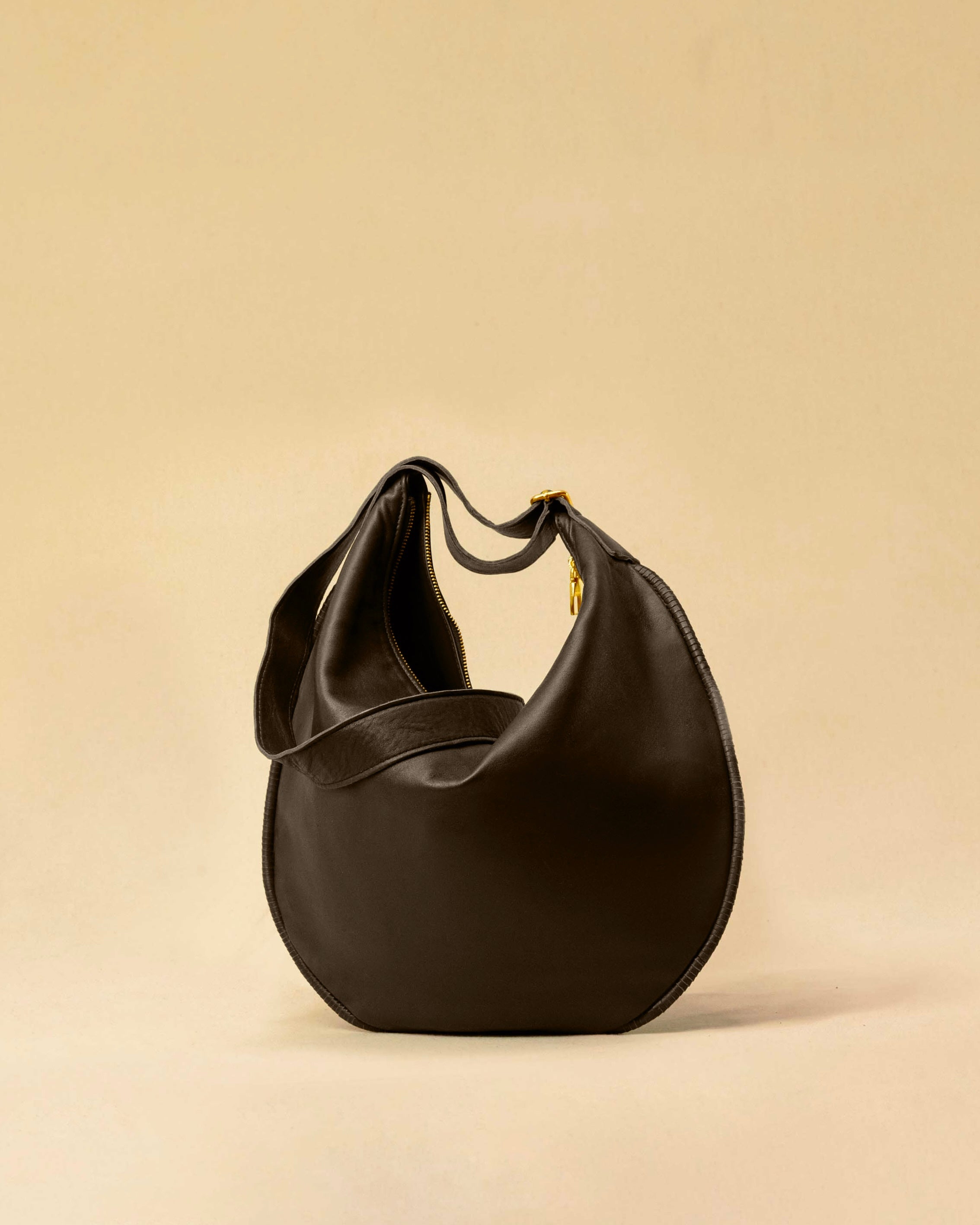 The Saddle Bag IVY by LABEL17 is crafted from supple, vegetable-tanned nappa leather and defined by its distinctive hand-stitched side seams. Its softly curved saddle silhouette rests comfortably against the body. The bag features a zip closure, a leather-lined interior, and a secure inner pocket. The adjustable strap allows it to be worn over the shoulder or crossbody – a versatile piece for everyday use. Handmade in Morocco.