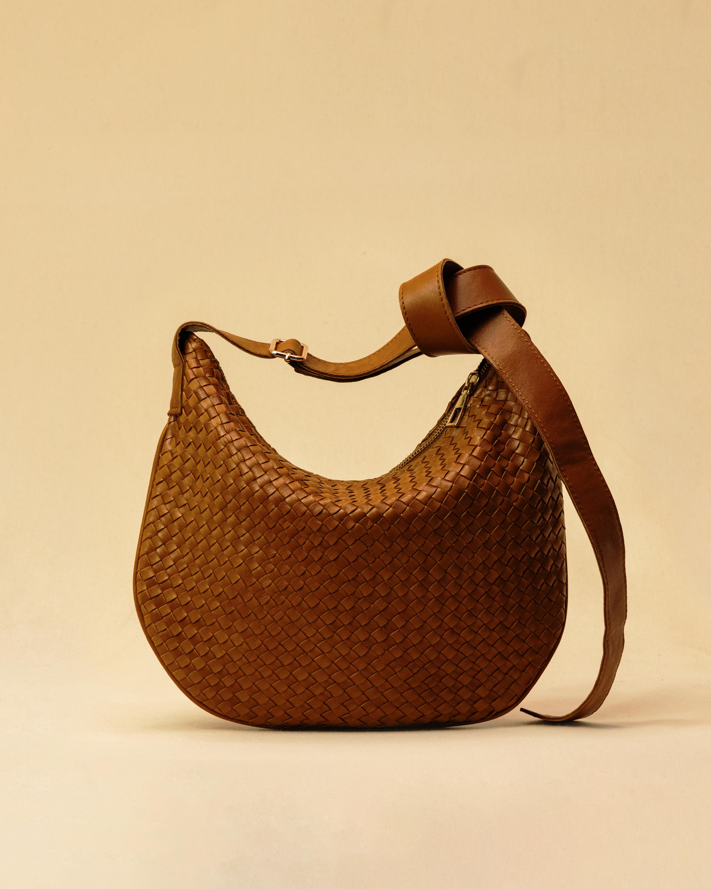 Die SHOULDER BAG SADDLE LUNA Medium in Cognac von LABEL17 ist aus feinstem, pflanzlich gegerbtem Nappaleder von Hand geflochten. Die Tasche hat einen Reissverschluss und einen ledergefütterten Innenraum mit Seitenfach. Dank dem verstellbaren Schulterriemen ist sie als Schultertasche oder Crossbody zu tragen.