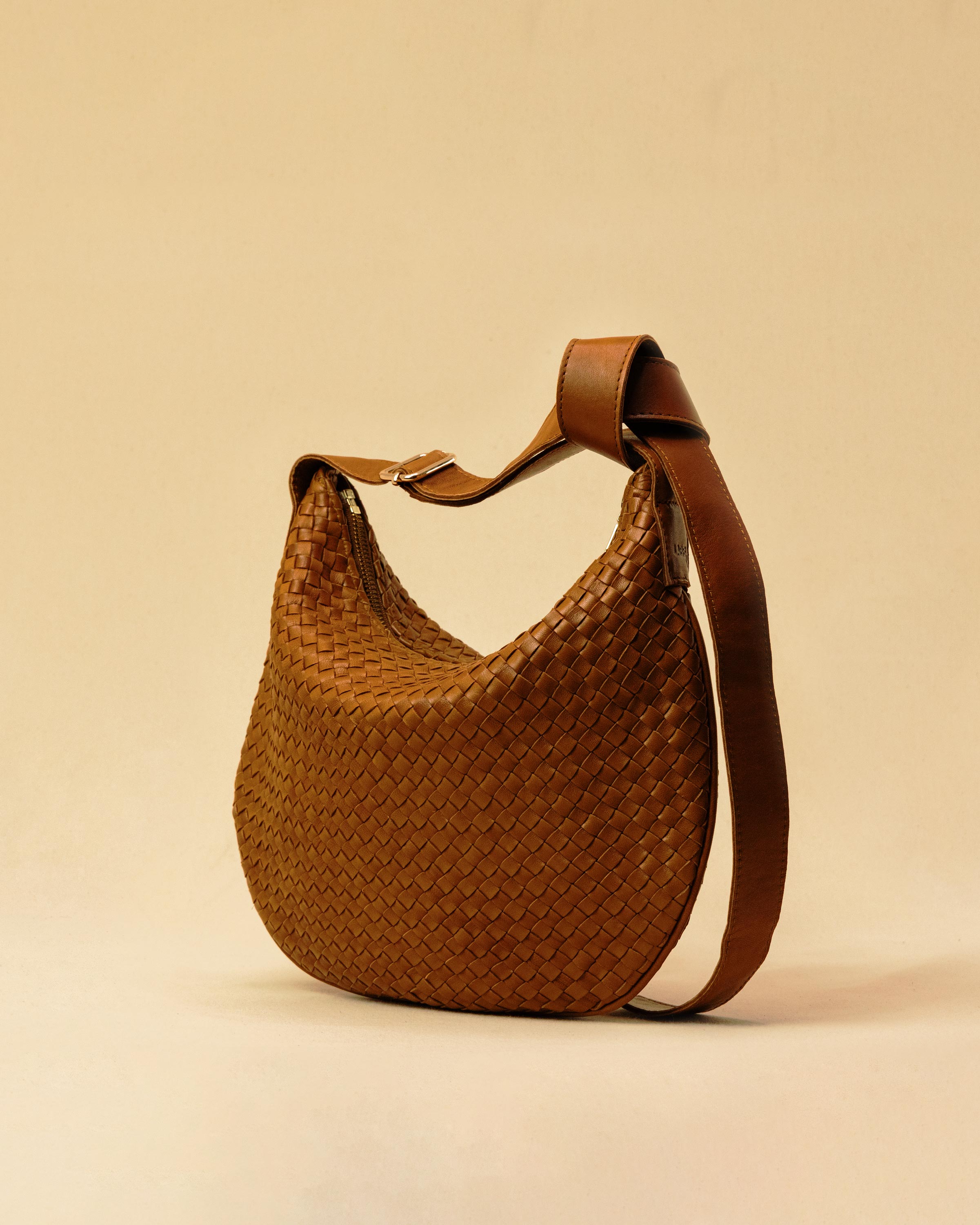 Die SHOULDER BAG SADDLE LUNA Medium in Cognac von LABEL17 ist aus feinstem, pflanzlich gegerbtem Nappaleder von Hand geflochten. Die Tasche hat einen Reissverschluss und einen ledergefütterten Innenraum mit Seitenfach. Dank dem verstellbaren Schulterriemen ist sie als Schultertasche oder Crossbody zu tragen.