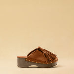 Clogs CHOUCHA in Cognac by LABEL17, crafted from supple, vegetable-tanned lamb nappa leather. A large, soft pompom on top swings elegantly from left to right with each step, adding a playful yet refined touch. The shoe features a durable sole for comfort and stability. The artisanal craftsmanship enhances the overall aesthetic, making these clogs a true statement piece. Quiet luxury at its best. Handmade in Greece.