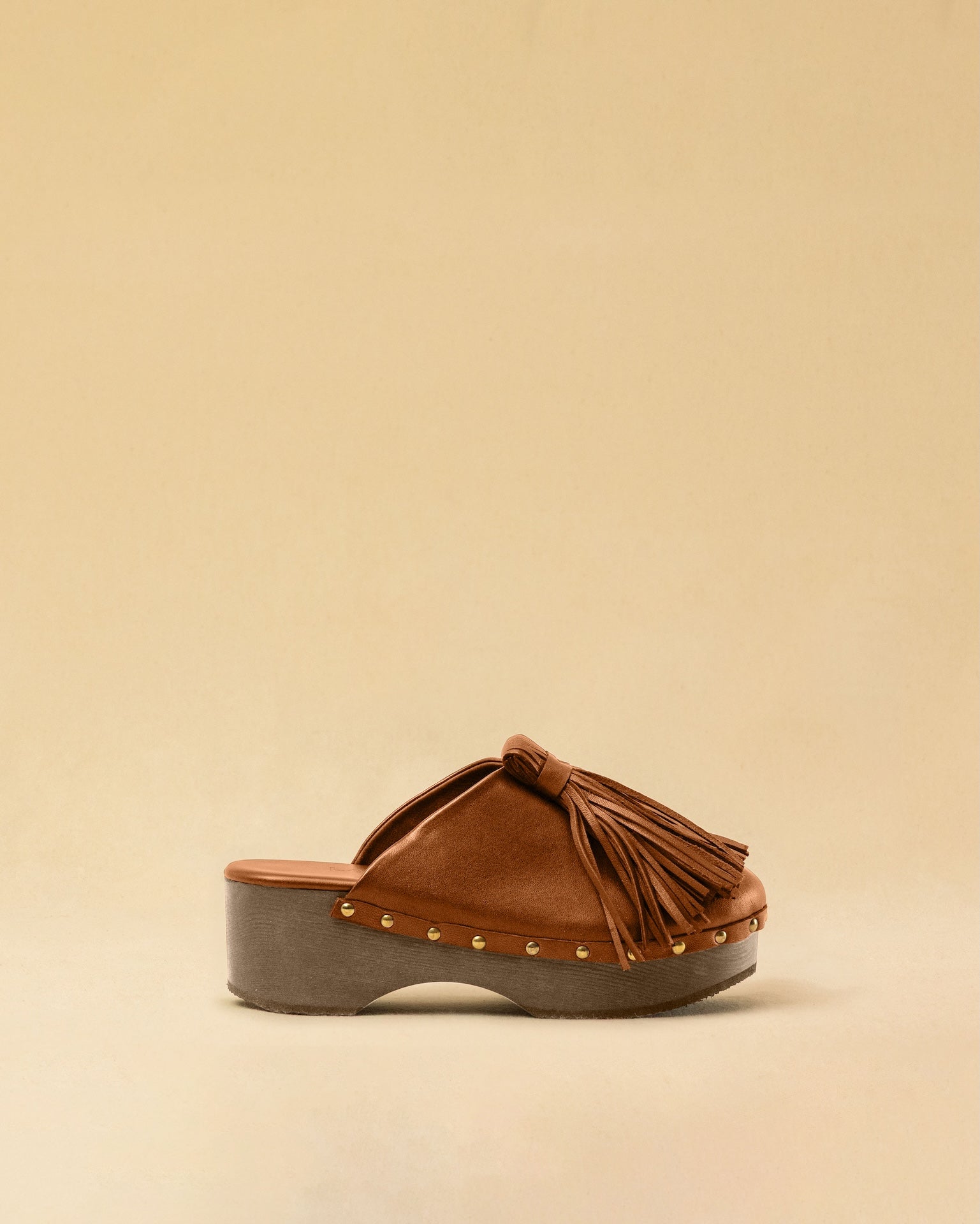 Clogs CHOUCHA in Cognac by LABEL17, crafted from supple, vegetable-tanned lamb nappa leather. A large, soft pompom on top swings elegantly from left to right with each step, adding a playful yet refined touch. The shoe features a durable sole for comfort and stability. The artisanal craftsmanship enhances the overall aesthetic, making these clogs a true statement piece. Quiet luxury at its best. Handmade in Greece.