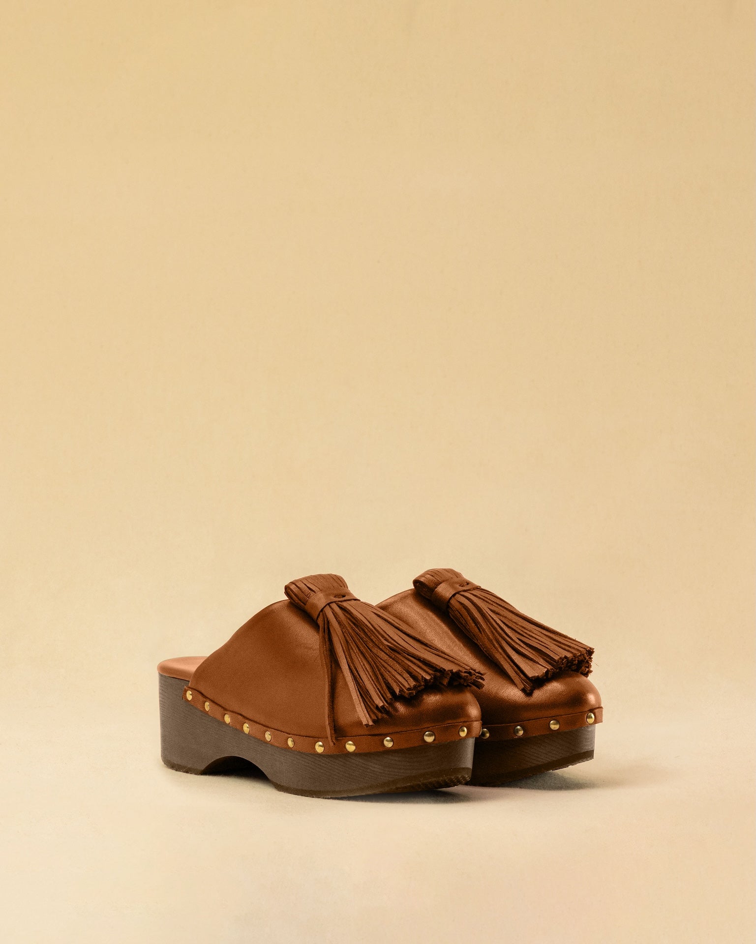 Clogs CHOUCHA in Cognac by LABEL17, crafted from supple, vegetable-tanned lamb nappa leather. A large, soft pompom on top swings elegantly from left to right with each step, adding a playful yet refined touch. The shoe features a durable sole for comfort and stability. The artisanal craftsmanship enhances the overall aesthetic, making these clogs a true statement piece. Quiet luxury at its best. Handmade in Greece.