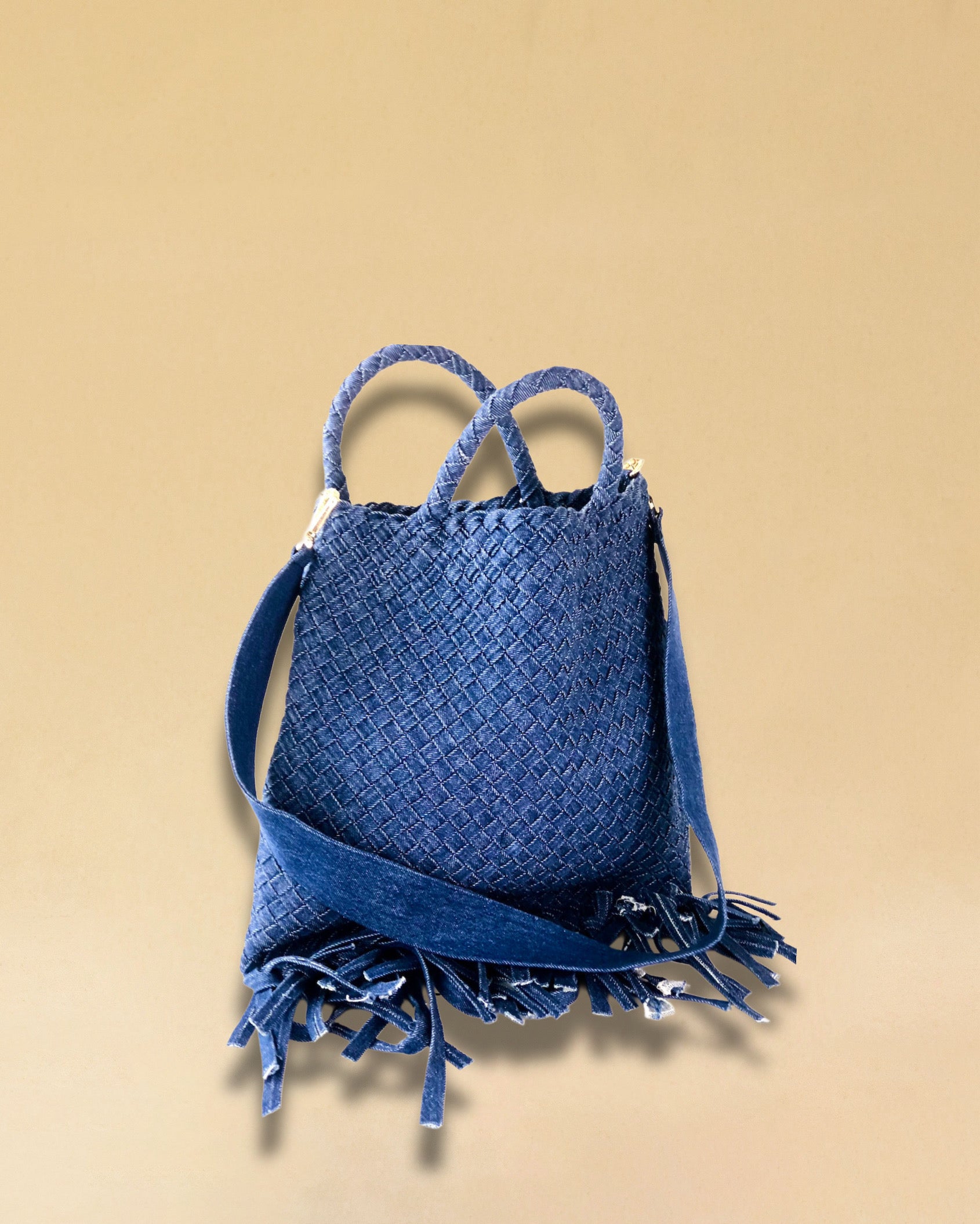 Die Crossbody Bag Tresse Fringes Denim von LABEL17 mit geflochtenen Henkeln und langem abnehmbarem Schulterriemen, ist aus gewaschenem Denim gefertigt und von Hand geflochten.