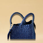 Die Crossbody Bag Tresse Fringes Denim von LABEL17 mit geflochtenen Henkeln und langem abnehmbarem Schulterriemen, ist aus gewaschenem Denim gefertigt und von Hand geflochten.