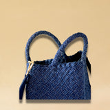 Die Crossbody Bag Tresse Fringes Denim von LABEL17 mit geflochtenen Henkeln und langem abnehmbarem Schulterriemen, ist aus gewaschenem Denim gefertigt und von Hand geflochten.