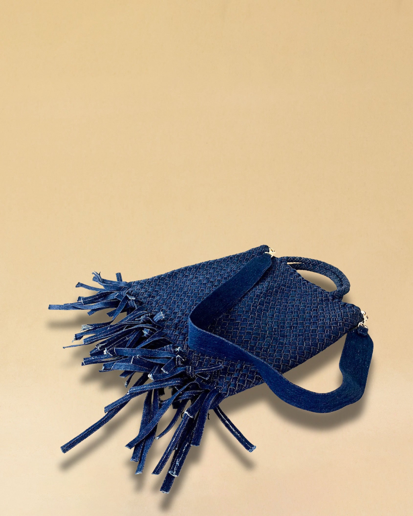 Die Crossbody Bag Tresse Fringes Denim von LABEL17 mit geflochtenen Henkeln und langem abnehmbarem Schulterriemen, ist aus gewaschenem Denim gefertigt und von Hand geflochten.