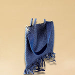 Die Crossbody Bag Tresse Fringes Denim von LABEL17 mit geflochtenen Henkeln und langem abnehmbarem Schulterriemen, ist aus gewaschenem Denim gefertigt und von Hand geflochten.