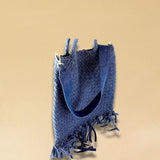 Die Crossbody Bag Tresse Fringes Denim von LABEL17 mit geflochtenen Henkeln und langem abnehmbarem Schulterriemen, ist aus gewaschenem Denim gefertigt und von Hand geflochten.