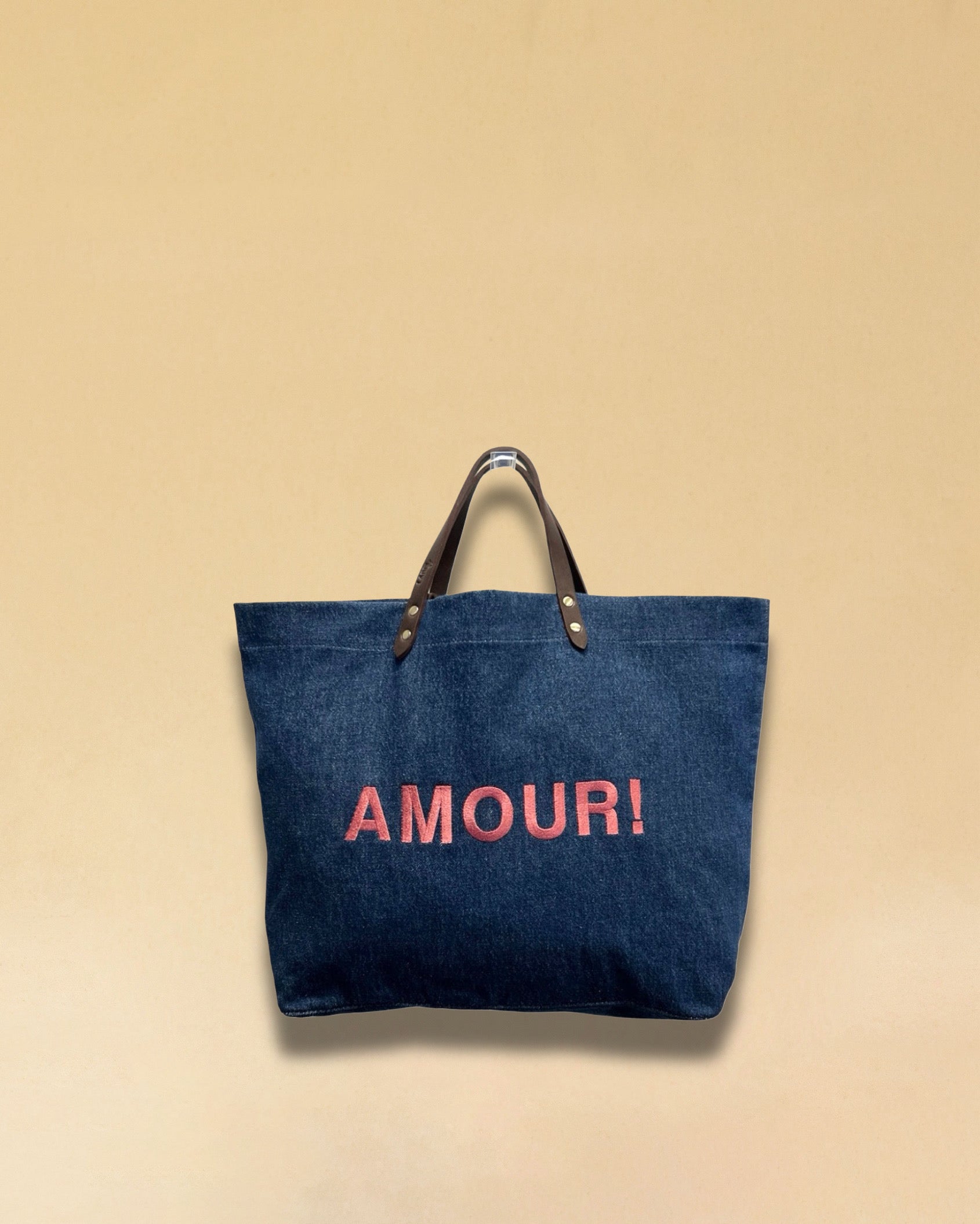 Bestickte Stofftasche von LABEL17 mit braunen Lederhenkeln und AMOUR
Botschaft auf der Vorderseite. Hergestellt in Marokko