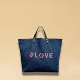 Bestickte Stofftasche von LABEL17 mit braunen Lederhenkeln und #LOVE Botschaft auf der Vorderseite. Hergestellt in Marokko