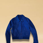 Die Lederjacke AMAL von LABEL17 in Azur-Bluelau besticht durch die kurze und figurschmeichelnde Passform. Sie harmoniert perfekt mit unserem Lederrock JACKIE. Gefertigt aus feinem Veloursleder, ist sie ein zeitloses Highlight für die Garderobe.