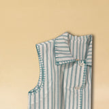 Unsere Vest LINDA aus hochwertiger Baumwolle ist eine ärmellose Veste, veredelt mit einem handgenähten Zierstich (Hbik-Stitch) in Türkis entlang der Knopfleiste, dem Kragen und dem Armloch.