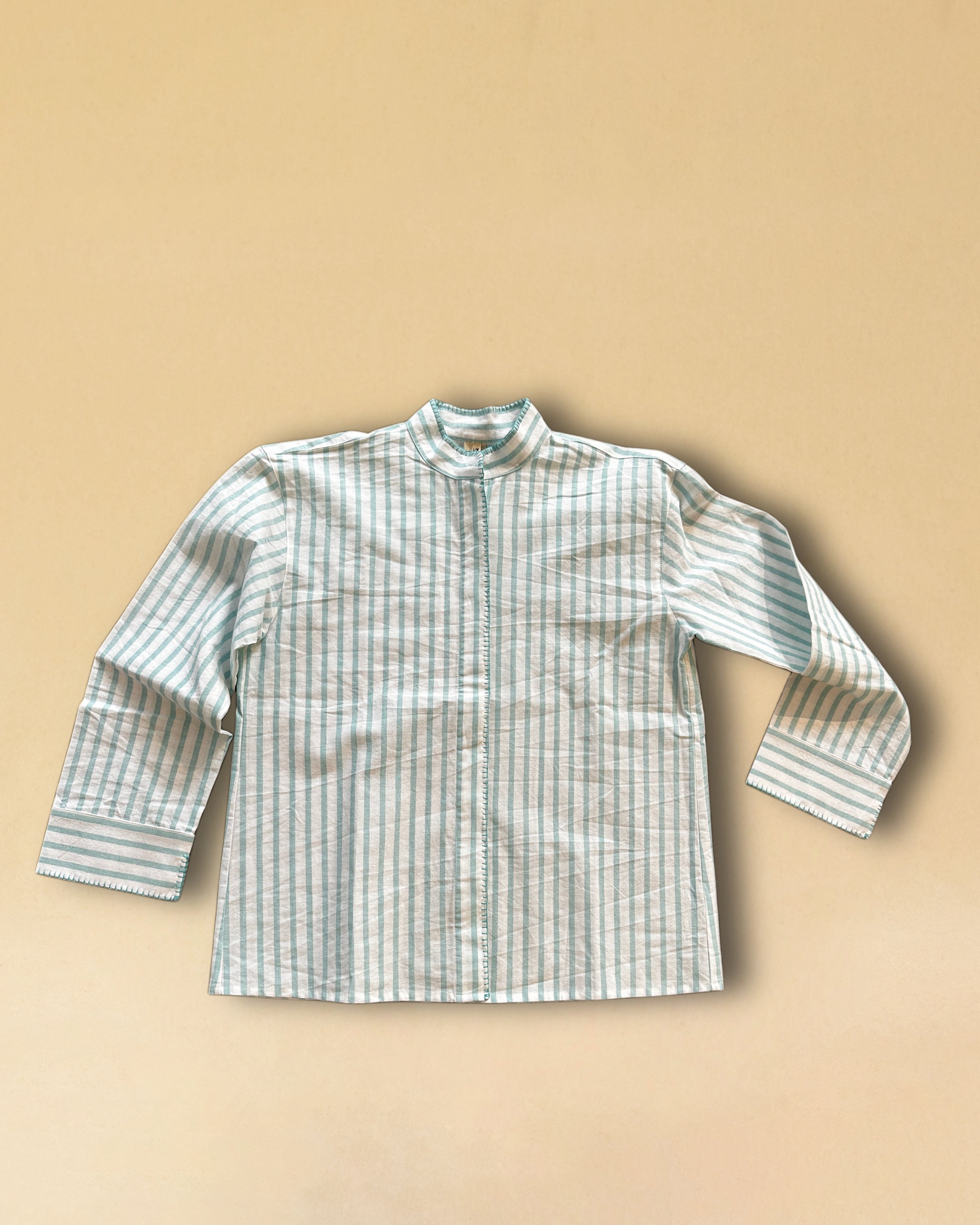 LABEL17's Blouse MANDY aus hochwertiger Baumwolle hat einen Stehkragen und eine gedeckte Knopfleiste, veredelt mit einem handgenähten Zierstich (Hbik-Stitch) in Türkis entlang der Knopfleiste, dem Kragen und der Manschette.