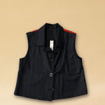 Die Vest LACE in Night Blue aus hochwertigem Baumwollmischgewebe besticht durch ihre elegante Spitzenapplikation in Rot auf dem Rücken – ein kühnes Detail, das dem schlichten Gilet eine dramatische Note verleiht. Knopfverschluss und ärmelloser Schnitt machen sie zum vielseitigen Stück für besondere Anlässe.