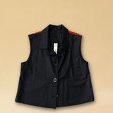 Die Vest LACE in Night Blue aus hochwertigem Baumwollmischgewebe besticht durch ihre elegante Spitzenapplikation in Rot auf dem Rücken – ein kühnes Detail, das dem schlichten Gilet eine dramatische Note verleiht. Knopfverschluss und ärmelloser Schnitt machen sie zum vielseitigen Stück für besondere Anlässe.