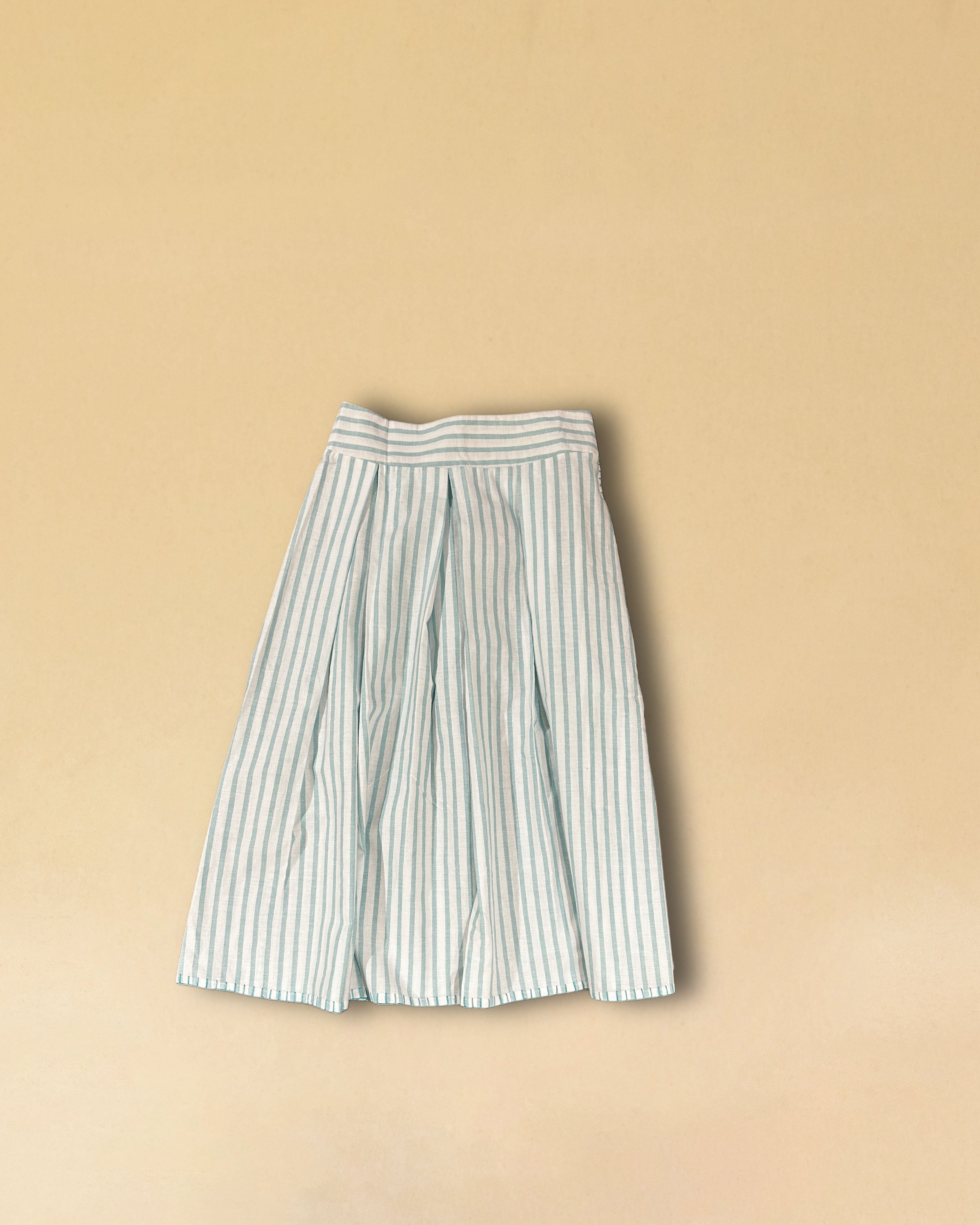 LABEL17's Skirt LINA ist ein Faltenrock aus Baumwolle, veredelt mit einem handgenähten Zierstich (Hbik-Stitch) an der linken und rechten Seite. Falten auf der Vorderseite und ein elastischer Einsatz am Rücken sorgen für angenehmen Tragekomfort. Perfekt für den Sommer.