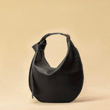 The Saddle Bag IVY by LABEL17 is crafted from supple, vegetable-tanned nappa leather and defined by its distinctive hand-stitched side seams. Its softly curved saddle silhouette rests comfortably against the body. The bag features a zip closure, a leather-lined interior, and a secure inner pocket. The adjustable strap allows it to be worn over the shoulder or crossbody – a versatile piece for everyday use. Handmade in Morocco.