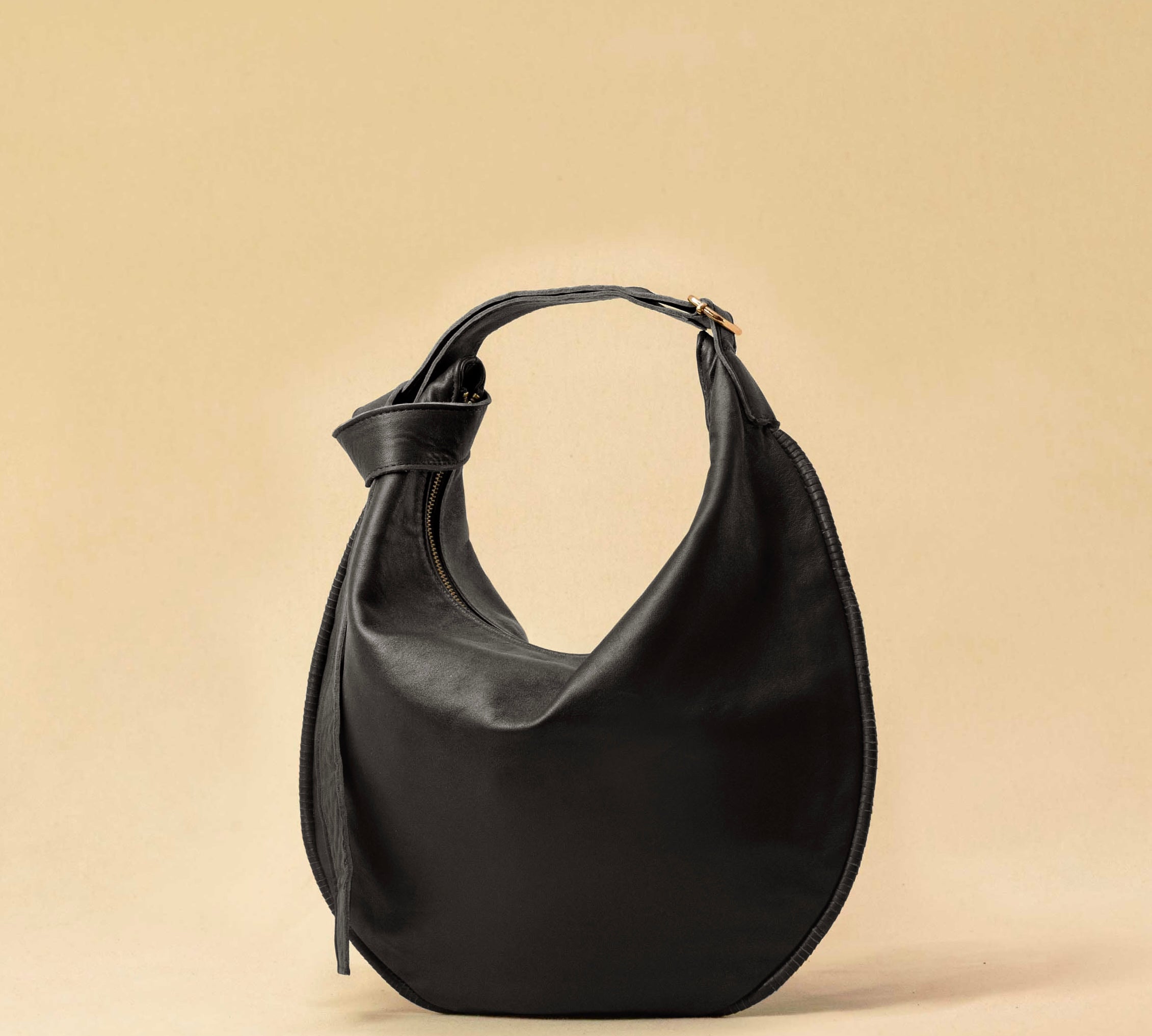 The Saddle Bag IVY by LABEL17 is crafted from supple, vegetable-tanned nappa leather and defined by its distinctive hand-stitched side seams. Its softly curved saddle silhouette rests comfortably against the body. The bag features a zip closure, a leather-lined interior, and a secure inner pocket. The adjustable strap allows it to be worn over the shoulder or crossbody – a versatile piece for everyday use. Handmade in Morocco.