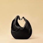 The Saddle Bag IVY by LABEL17 is crafted from supple, vegetable-tanned nappa leather and defined by its distinctive hand-stitched side seams. Its softly curved saddle silhouette rests comfortably against the body. The bag features a zip closure, a leather-lined interior, and a secure inner pocket. The adjustable strap allows it to be worn over the shoulder or crossbody – a versatile piece for everyday use. Handmade in Morocco.