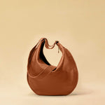 The Saddle Bag IVY by LABEL17 is crafted from supple, vegetable-tanned nappa leather and defined by its distinctive hand-stitched side seams. Its softly curved saddle silhouette rests comfortably against the body. The bag features a zip closure, a leather-lined interior, and a secure inner pocket. The adjustable strap allows it to be worn over the shoulder or crossbody – a versatile piece for everyday use. Handmade in Morocco.