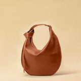 The Saddle Bag IVY by LABEL17 is crafted from supple, vegetable-tanned nappa leather and defined by its distinctive hand-stitched side seams. Its softly curved saddle silhouette rests comfortably against the body. The bag features a zip closure, a leather-lined interior, and a secure inner pocket. The adjustable strap allows it to be worn over the shoulder or crossbody – a versatile piece for everyday use. Handmade in Morocco.