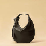 The Saddle Bag IVY by LABEL17 is crafted from supple, vegetable-tanned nappa leather and defined by its distinctive hand-stitched side seams. Its softly curved saddle silhouette rests comfortably against the body. The bag features a zip closure, a leather-lined interior, and a secure inner pocket. The adjustable strap allows it to be worn over the shoulder or crossbody – a versatile piece for everyday use. Handmade in Morocco.