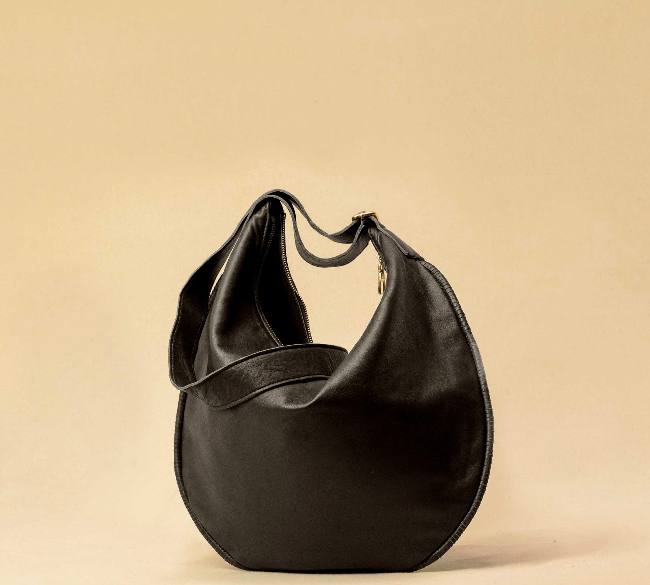 The Saddle Bag IVY by LABEL17 is crafted from supple, vegetable-tanned nappa leather and defined by its distinctive hand-stitched side seams. Its softly curved saddle silhouette rests comfortably against the body. The bag features a zip closure, a leather-lined interior, and a secure inner pocket. The adjustable strap allows it to be worn over the shoulder or crossbody – a versatile piece for everyday use. Handmade in Morocco.