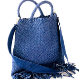 Die Crossbody Bag Tresse Fringes Denim von LABEL17 mit geflochtenen Henkeln und langem abnehmbarem Schulterriemen, ist aus gewaschenem Denim gefertigt und von Hand geflochten.