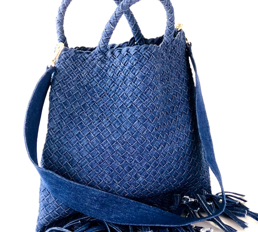 Die Crossbody Bag Tresse Fringes Denim von LABEL17 mit geflochtenen Henkeln und langem abnehmbarem Schulterriemen, ist aus gewaschenem Denim gefertigt und von Hand geflochten.