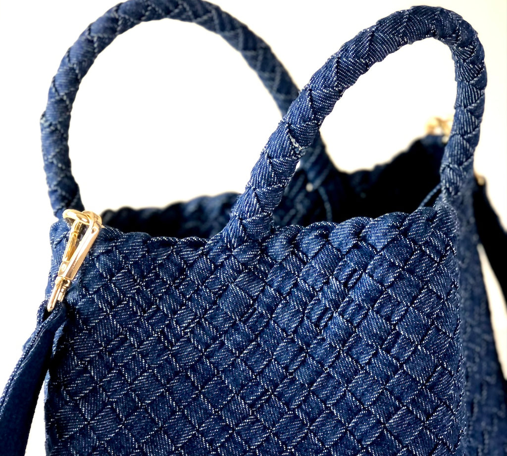 Die Crossbody Bag Tresse Fringes Denim von LABEL17 mit geflochtenen Henkeln und langem abnehmbarem Schulterriemen, ist aus gewaschenem Denim gefertigt und von Hand geflochten.