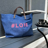 Bestickte Stofftasche von LABEL17 mit braunen Lederhenkeln und #LOVE Botschaft auf der Vorderseite. Hergestellt in Marokko