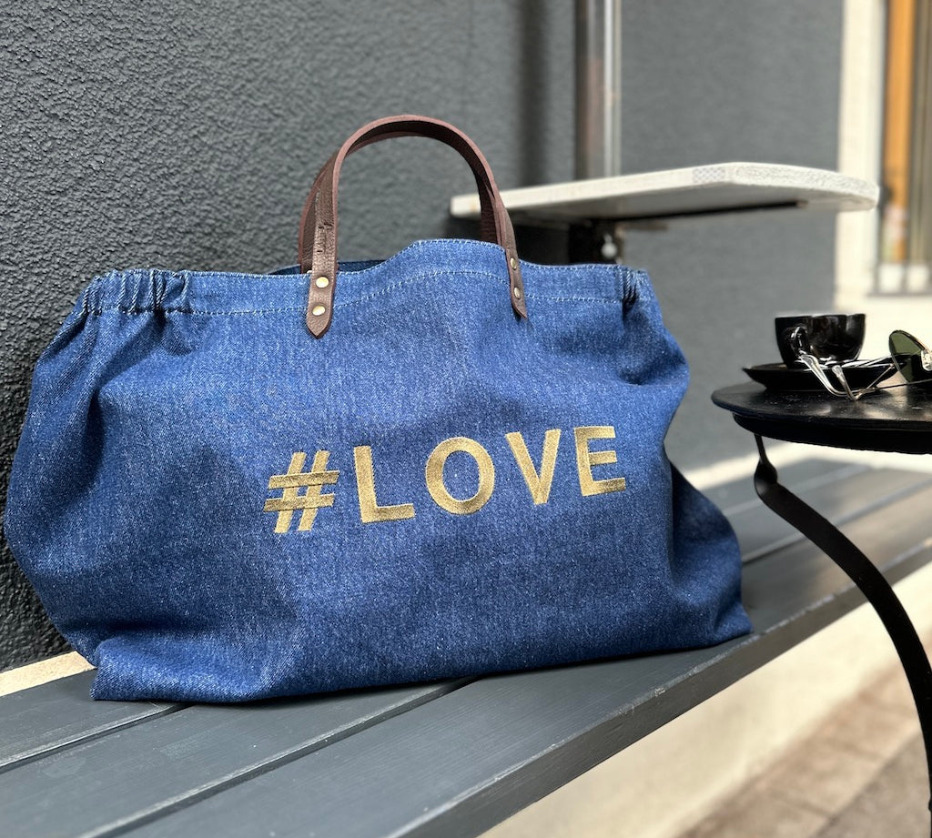 Bestickte Stofftasche von LABEL17 mit braunen Lederhenkeln und #LOVE Botschaft auf der Vorderseite. Hergestellt in Marokko