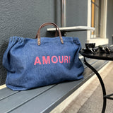 Bestickte Stofftasche von LABEL17 mit braunen Lederhenkeln und AMOUR Botschaft auf der Vorderseite. Hergestellt in Marokko