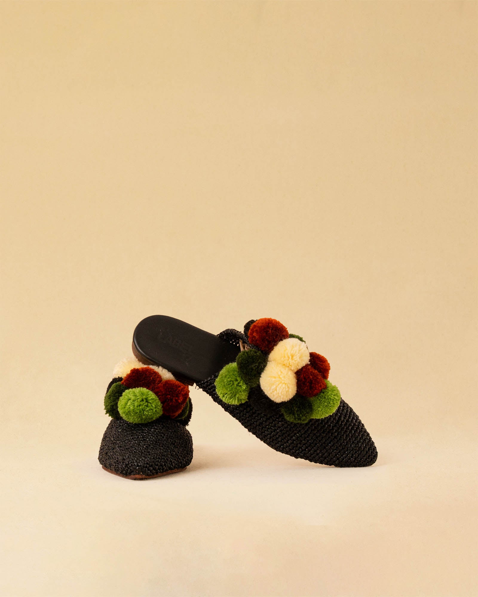 Leicht und verspielt bestechen die schwarzen Raffia Mules GELATO von LABEL17 durch die reduzierte Form und die farbigen Pompoms als Highlight. Von Hand geflochten, ein raffiniertes Essential für den Sommer.