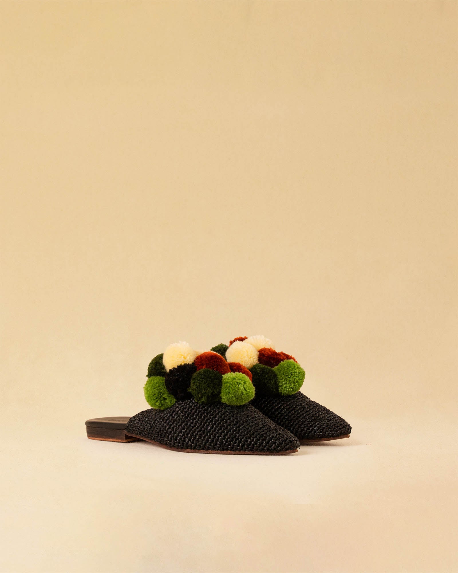 Leicht und verspielt bestechen die schwarzen Raffia Mules GELATO von LABEL17 durch die reduzierte Form und die farbigen Pompoms als Highlight. Von Hand geflochten, ein raffiniertes Essential für den Sommer.