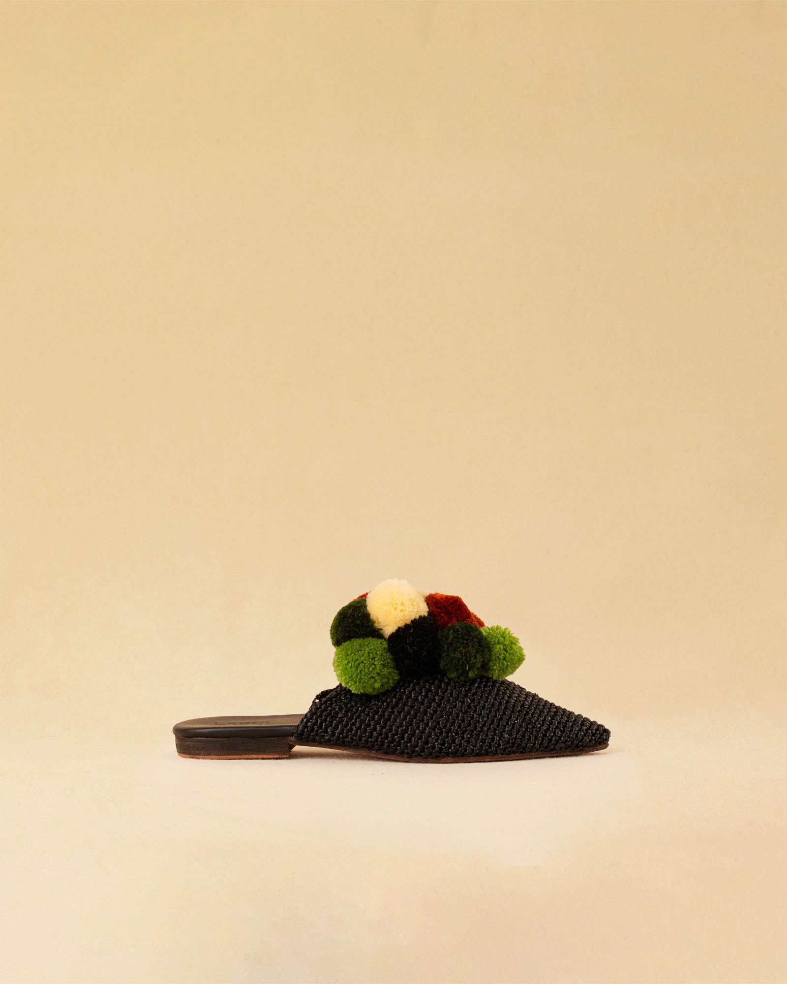 Leicht und verspielt bestechen die schwarzen Raffia Mules GELATO von LABEL17 durch die reduzierte Form und die farbigen Pompoms als Highlight. Von Hand geflochten, ein raffiniertes Essential für den Sommer.