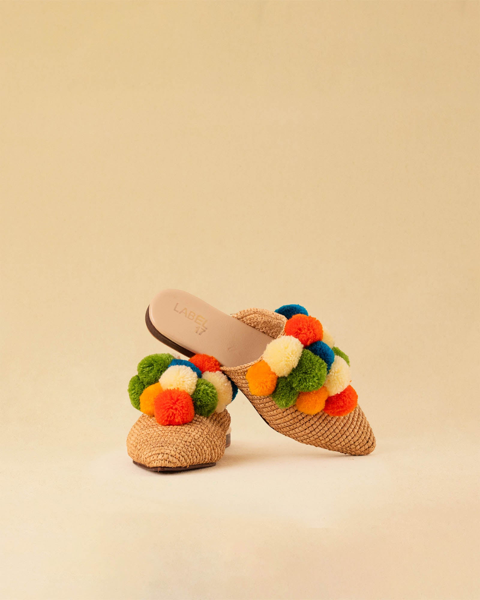 Leicht und verspielt bestechen die nuturfarbene Raffia Mules GELATO von LABEL17 durch die reduzierte Form und die farbigen Pompoms als Highlight. Von Hand geflochten, ein raffiniertes Essential für den Sommer.