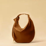 The Saddle Bag IVY by LABEL17 is crafted from supple, vegetable-tanned nappa leather and defined by its distinctive hand-stitched side seams. Its softly curved saddle silhouette rests comfortably against the body. The bag features a zip closure, a leather-lined interior, and a secure inner pocket. The adjustable strap allows it to be worn over the shoulder or crossbody – a versatile piece for everyday use. Handmade in Morocco.